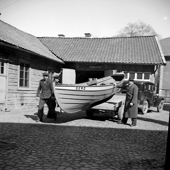 På Qvänsels bakgård, Skara.
Evert "Siki" Andersson vid upprustad båt (döpt till Gerd efter en dotter) klar för sjösättning. Bakom Andersson järnvägaren, båtbyggaren och fiskaren Frans Bolinder, 1936.