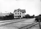 Skara första stationshus. 
På bilden återfinns två tågset, ett mot Stenstorp och ett mot Lidköping. Loken är de första L.S.S.J. (Lidköping-Skara-Stenstorps Jernväg) inköpte hos Kristinehamns mek. verkstad 1873 och betingade ett pris av 24000 å 24500 riksdaler per styck. Fotografi från 1878.