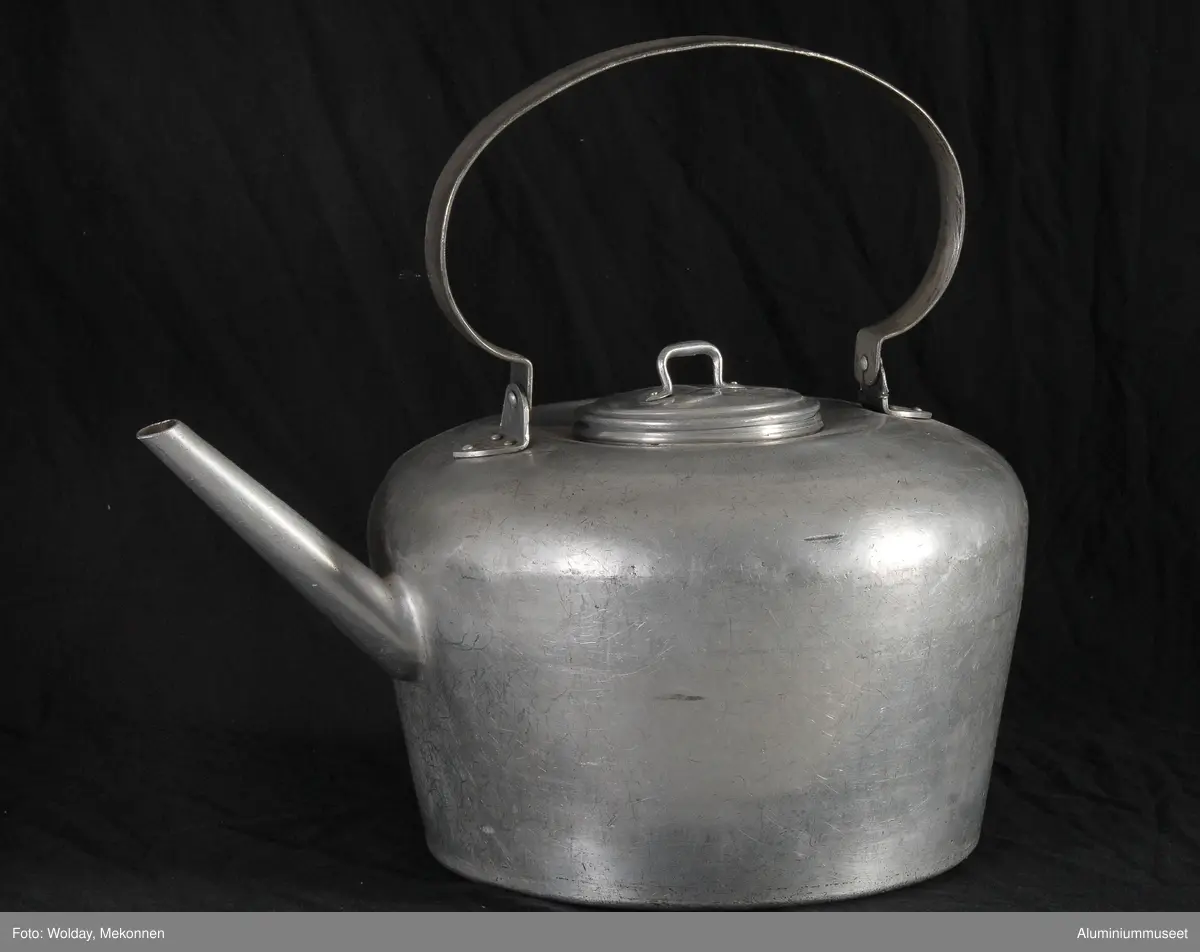 Teknikk: Kjelen er håndlaget på blikkenslagerverkstedet. Selve kjelen er laget i tre deler som er sveiset sammen. Tuten er håndlaget.  Lokket er lokk til melkespann art. nr. 21,  14 cm.
Håndtak og ører er håndlaget på blikkenslagerverkstedet.
Form: Konisk form med tynn bund.
