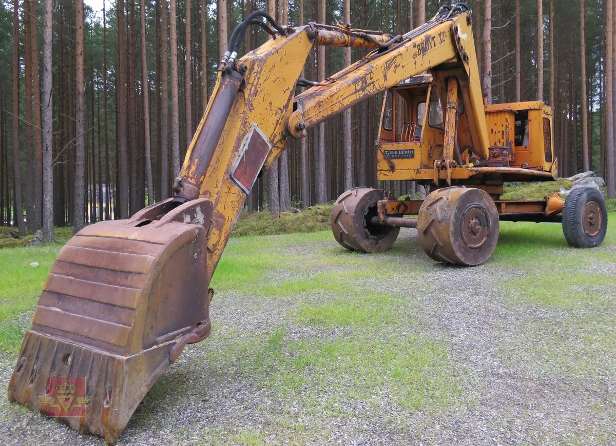 Gravemaskin, hjulgående. 2 jernhjul foran og 2 gummihjul bak. Maskinen er oransje med svart sete. Motoren er en 4-sylindret dieseldrevet type fra Perkins. Gravemaskinen var ikke selvgående, men forflyttet seg med gravearmen under arbeid. Ved transport mellom arbeidsstedene hektet en skuffen i lasteplanet og løftet opp "forhjulene" slik at den ble transportert som en henger.