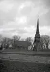 En klockstapel, kyrkogård och kyrka. Pelarne kyrka.