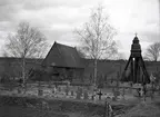 En klockstapel, kyrkogård och kyrka. Djursdala kyrka.