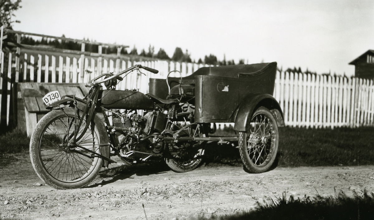 Gammel motorsykkel i Galåsen  Indian nr. D 730 (motorsykkel med vogn), stående på veien ved gjerde. Skolehuset helt til høyre.