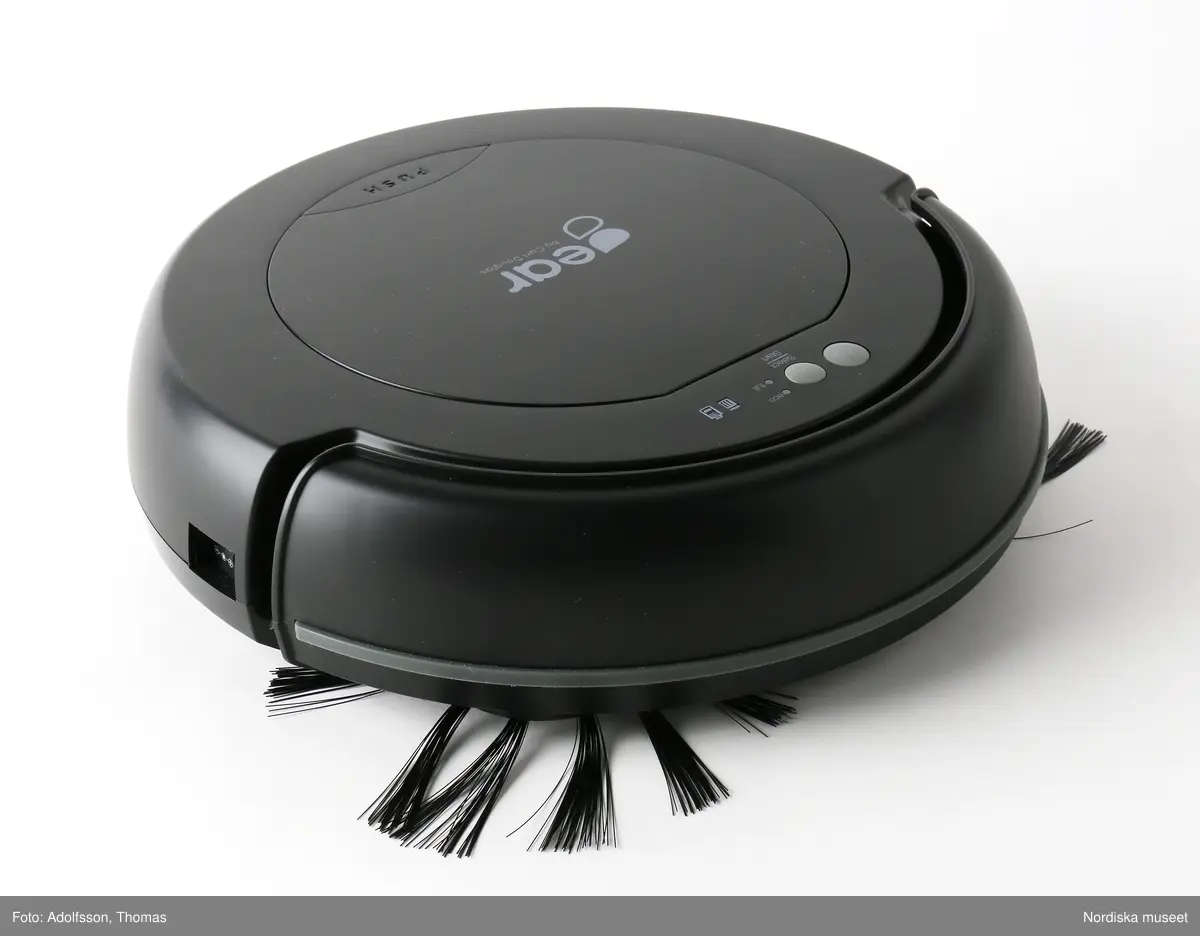 Automatisk hushållsdammsugare, så kallad minirobotdammsugare, Robot Vacuum Cleaner Frank av märket Gear by Carl Douglas. Dammsugaren en låg cylinder av svart plast. Stötdämpare längs en del av kanten. På ovansidan kontrollpanel med strömbrytare samt en lucka med texten "Gear by Carl Douglas" innehållande dammbehållare och filter.

Undertill finns intagsventil för damm och smuts, två drivhjul, ett litet främre hjul och två runda sidoborstar med långa spröt av nylontrådar. Här finns också en dammpappershållare med fastsittande dammpapper för moppning, en batterilucka och trappsensorer. Batteriet förvärvas av bevarandeskäl inte utan återvinns efter fotografering. Till dammsugaren hör också en adapter med svart sladd och stickpropp samt en bruksanvisning, Robot Cleaner Frank User manual, på flera språk.
/Maria Maxén 2017-01-11