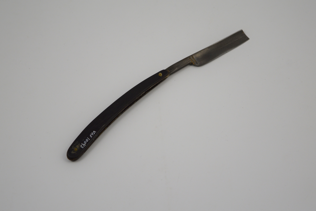 Sammenleggbar barberkniv med rett egg. Knivbladet har konisk tverrsnitt. Bladet munner ut i tynt skaft
med en krumning som holdegrep med fingeren. Skaftet er naglet fast til
kniven. Består av to deler som fungerer som beskyttelse i sammenlagt
stilling.