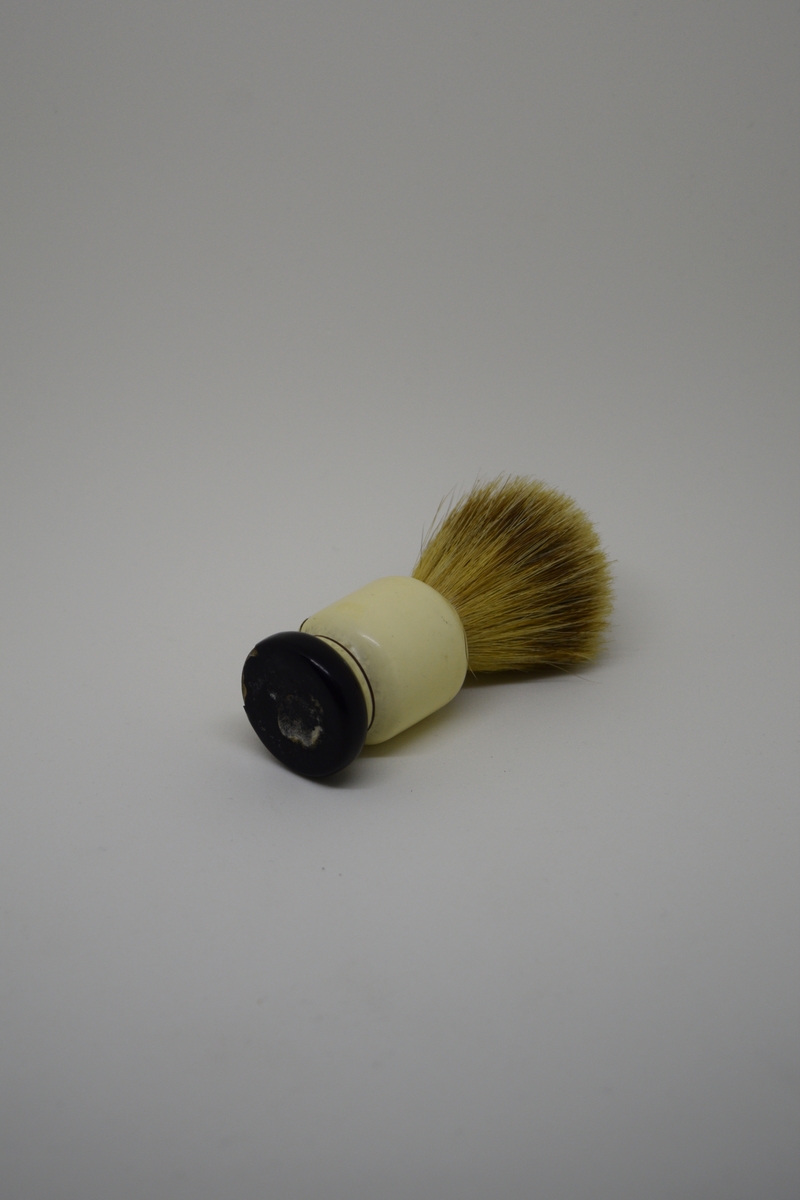 Barberkost med søyleformet skaft og en langsgående hulkil. Dreiet skaft/sokkel m/et stort hull. Bust tappet ned i dette. Holdt på plass av en lettmetallring. Malt og lakket.