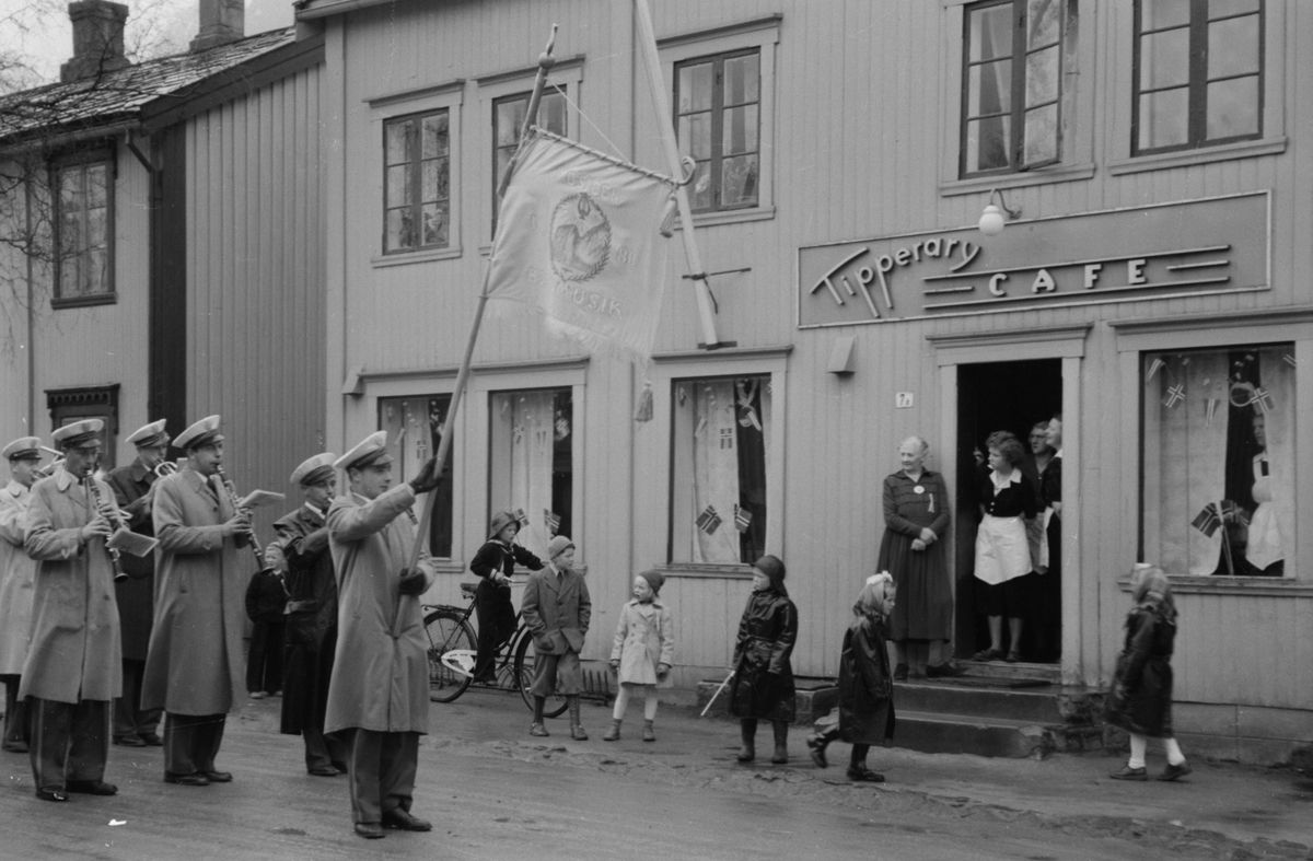 Olga Andersen og ei serveringsperso på trappa til Tipperary Cafe og Spiseforetning 17.mai 1951 mens de ser på Mosjøen Hornmusikk.