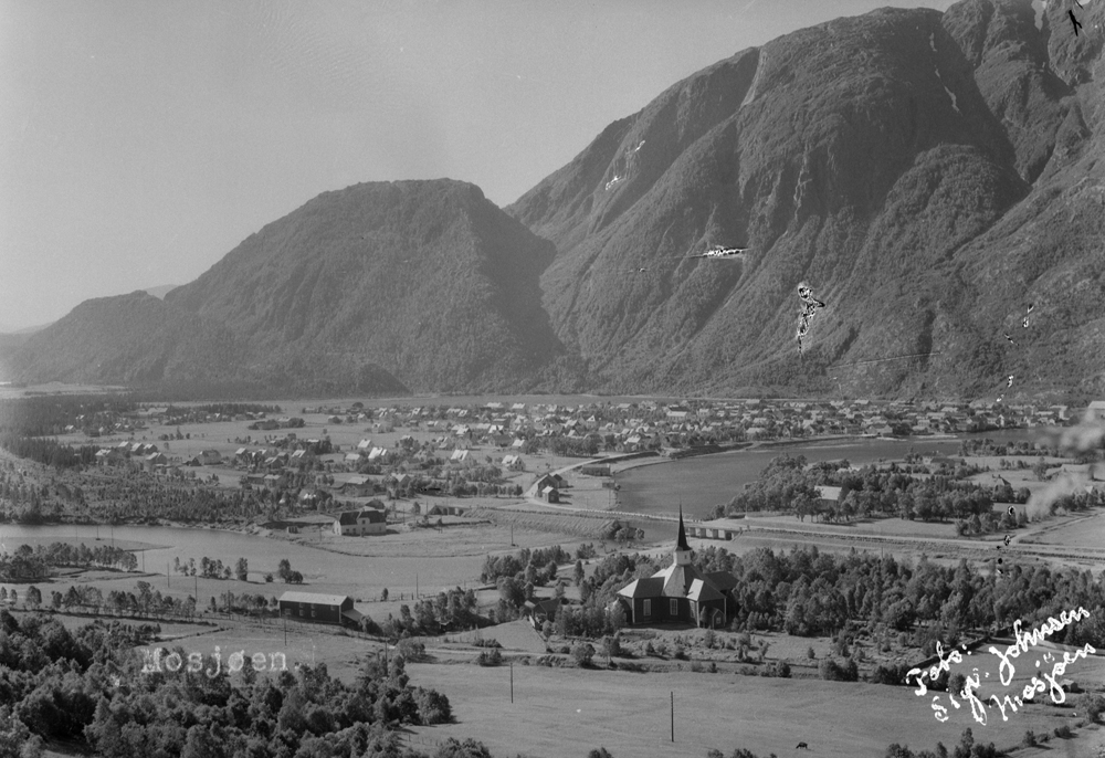 Oversikt over byflata med Kirka og bygdetunet i forgrunnen. Vi ser Dolstad kirke med hvitt tårn (t.o.m.1935) og jernbanebrua som ble ferdig i 1935.