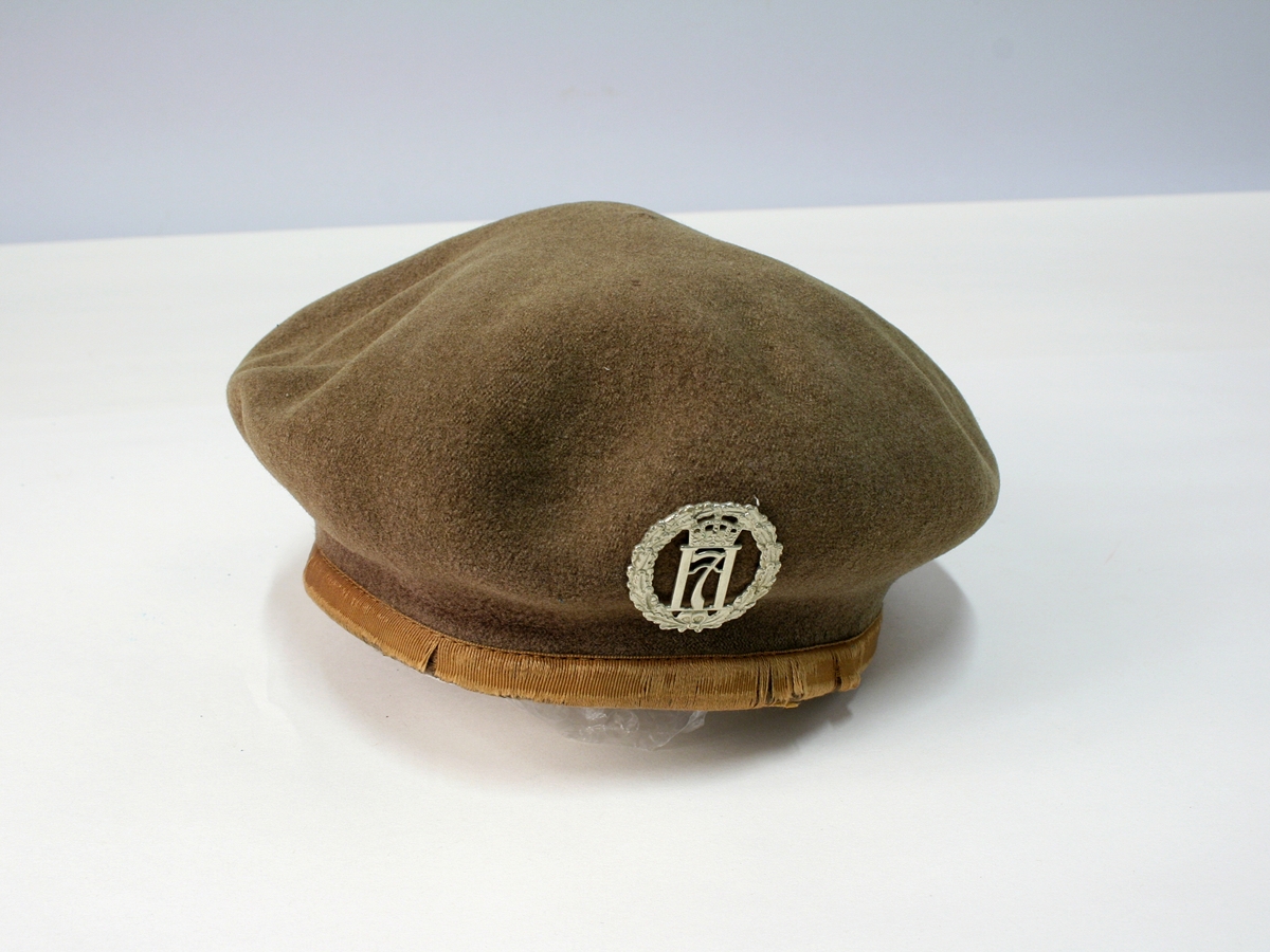 Brun-grønn beret med merke av metal.