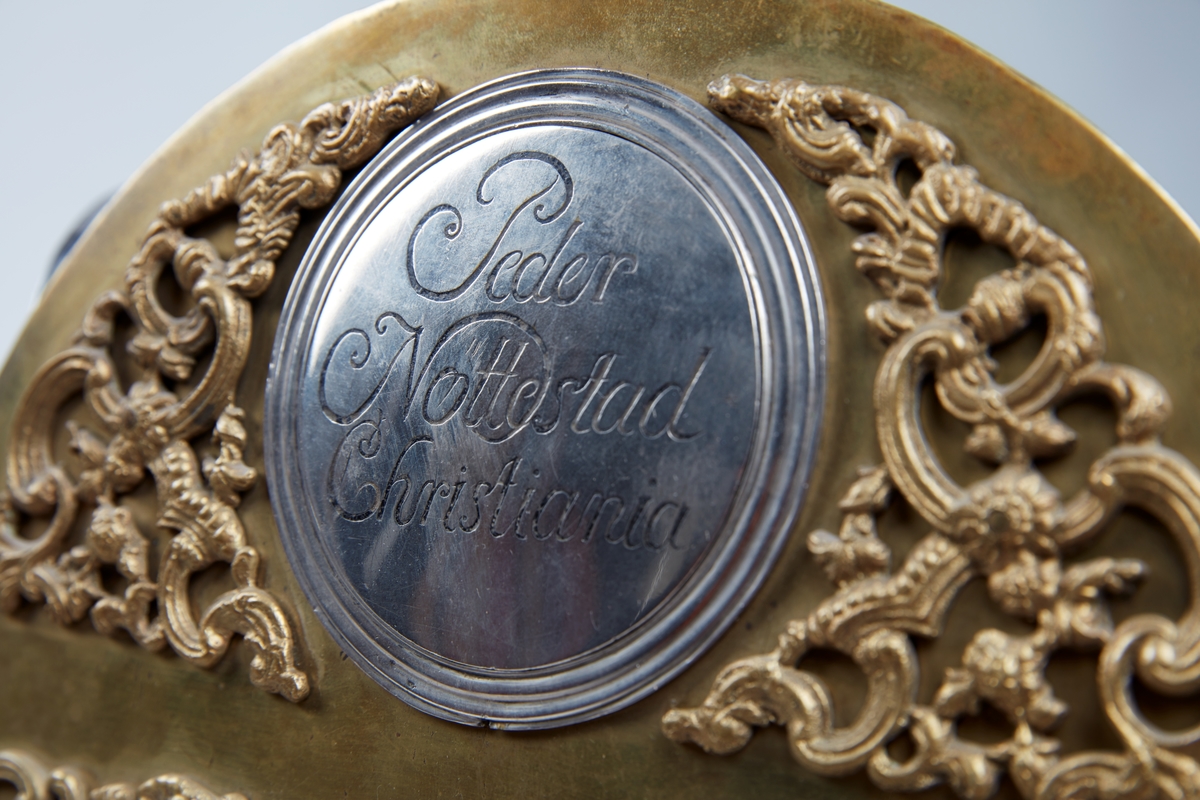 Gulvur i antatt sekundær kasse. Buet toppstykke med brutt gavl og vinduer til urverket på sidene. Rektangulær hoveddel med svungen sokkel nederst. Toppstykket dekorert med utskåret gitterverk øverst samt tre kuler på gesimsen og søyler på hver side av lysåpningen. Hoveddelen av kassen med pendeldøren er udekorert, sokkelen dekorert med utskåret gitterverk samt blader (akantus) på sidene og musling på midten nederst. Hele kassen malt ensfarget rød, kulene på gesimsen er sorte.

Urverk av messing forsynt med spillverk med elleve bjeller (visstnok til to melodier) samt én timeslagbjelle. Støpt dekor i tallskivens hjørner, hovedsakelig bladverk og c-formede ornamenter i et intrikat mønster. Midtfeltet er finhamret uten annen ornamentikk. Forsølvet timering og stjerneformet sekundring samt navneplate med signatur øverst og datoring som vises over sekstallet nederst.