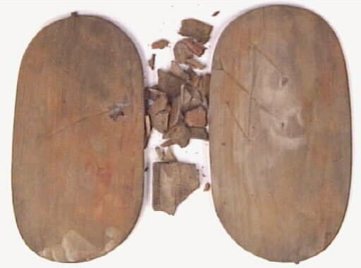 En svepask, i delar. Delarna utgörs av ett lock, en botten samt fragment av svepet. Locket och botten är båda försedda med varsitt bomärke.