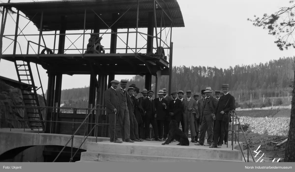 Gruppe menn ved byggverk, muligens en dam.