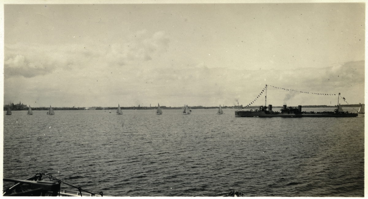 Vy av Tallinn från vattnet med mindre segelbåtar samt en jagare med stor flaggning. Jagaren är av Izjaslav-klass och bör därför vara LENNUK, ex AVTROIL, som tillföll Estland efter första världskriget. Bilden är tagen i samband med Gustaf V:s statsbesök i Tallinn i juni 1929.