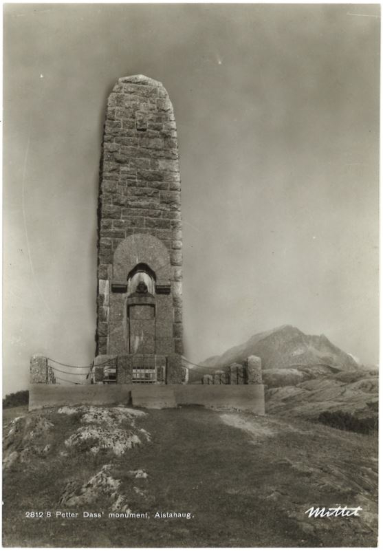 Svart/hvitt foto. Bauta over Petter Dass, med Vettfjellet i bakgrunnen.