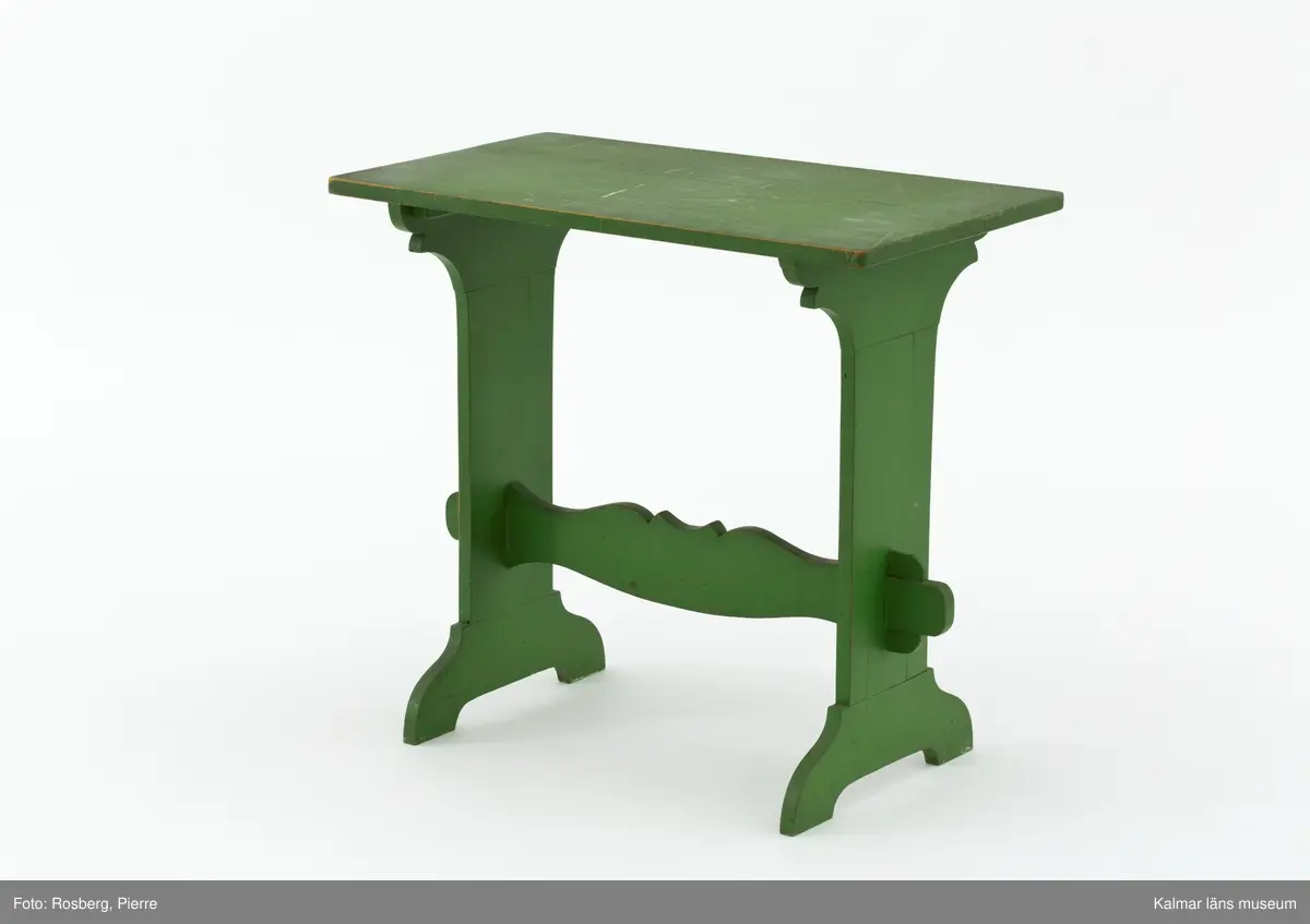 KLM 31918. Bord. Av trä, furu. Bord med två enkelståndare förenade med en profilerad regelbom. Ståndarna är nederst förgrenade på två fötter. Målad i grön färg.