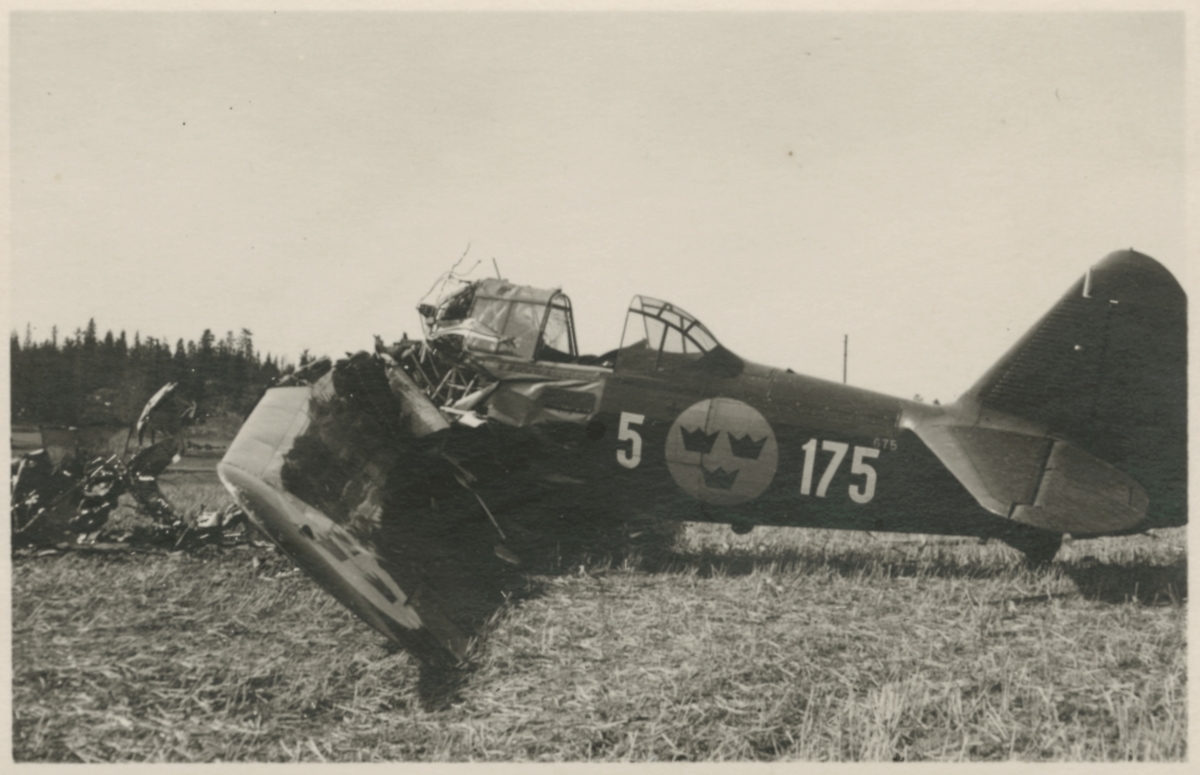 Havererat militärt skolflygplan SK 14 nummer 675, märkt F 5-175 på ett fält utanför Vittsäter, sydost om Nykil i Östergötland, den 30 april 1940. Män i närheten av flygplanet. Serie om 8 bilder.