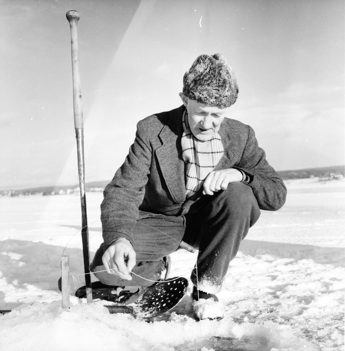 Man pimplar fisk på isen.