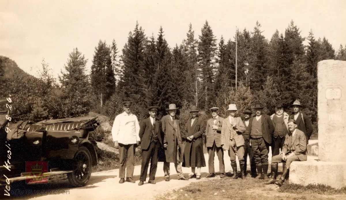 "Ved Krosli 09.08.1926", i følge merking på bildet. På bildet står et stort betongvegmerke med innhugget årstall: "Gjennem Vraadal 1904". Damen på bildet er muligens Christine Baalsrud, vegdirektørens kone. Han står til høyre for henne med skyggelue. Personene nr. 3 og nr. 6 fra venstre er de samme  som er avbildet på bilde NVM 00-F-3579. De er ukjente. 

De neste bildeframvisningene i farger viser "Vegmerke i Krossli." Sitat gjengitt fra Krossli-lokalhistoriewiki.no. Foto: Olav Momrak Haugan: "Krossli er eit vegkryss i Tokke kommune som ligg på vegen frå Bandaksli til Fyresdal. I 2011 går Rv 355 nordover frå Fyresdal til Krossli. Bandakslivegen, vegen fra Bandaksli til Fyresdal, vart i fyste del av 1900-talet grundig utbedra. Frå denne perioden finnast det fleire vegmerke som fortel vegfarande kor vegen fører vidare. Ei slik støtte stod midt i krysset i Krossli, i 2011 står den i utkanten av krysset. Litt lenger sør vert ein gjort merksam på at ein kryssar grensa til Fyresdal, etter fyrst å ha vore eit lite stykke gjennom Kvitseid kommune". 

Ref. til verneplanen "Vegvalg-Nasjonal verneplan for veger, bruer og vegrelaterte kulturminner. Statens vegvesen-Region Sør". Jfr. "202 Bandaksli", side 206. Se vedlegg.