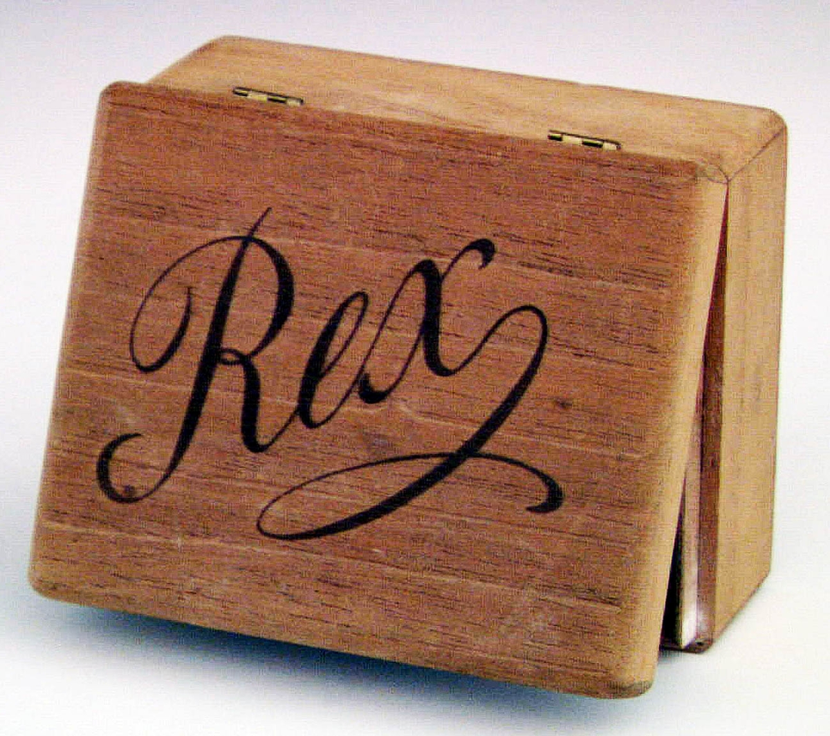Ask av trä märkt med lock försett med två gångjärn av mässing. Rex som text på locket. Har använts som nipperask.