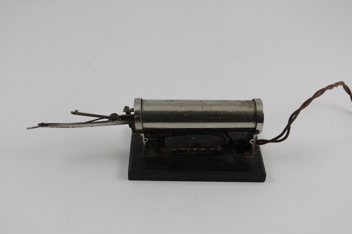 a) Krølltang består av to deler. Underdel som har vulstform, overdel rørformet og spent fast m/fjær til underdel. 
b) Varmeelement på sokkel m/elektrisk kobling.