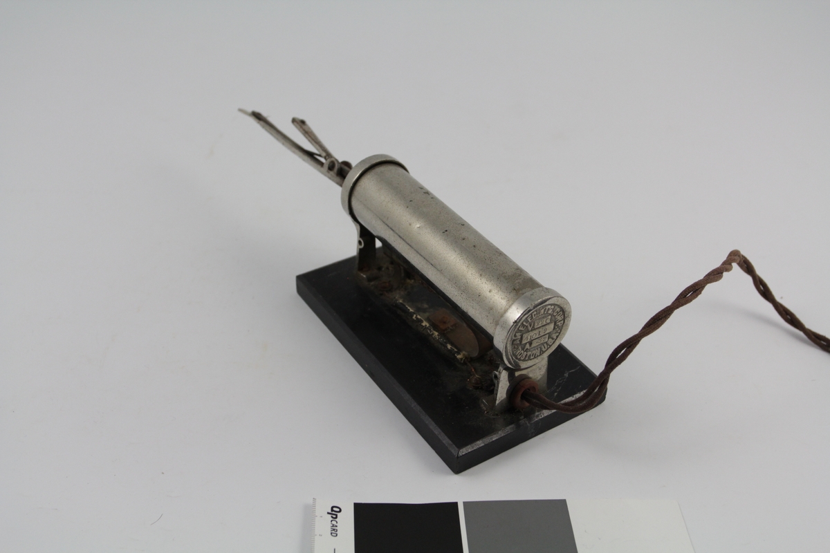 a) Krølltang består av to deler. Underdel som har vulstform, overdel rørformet og spent fast m/fjær til underdel. 
b) Varmeelement på sokkel m/elektrisk kobling.