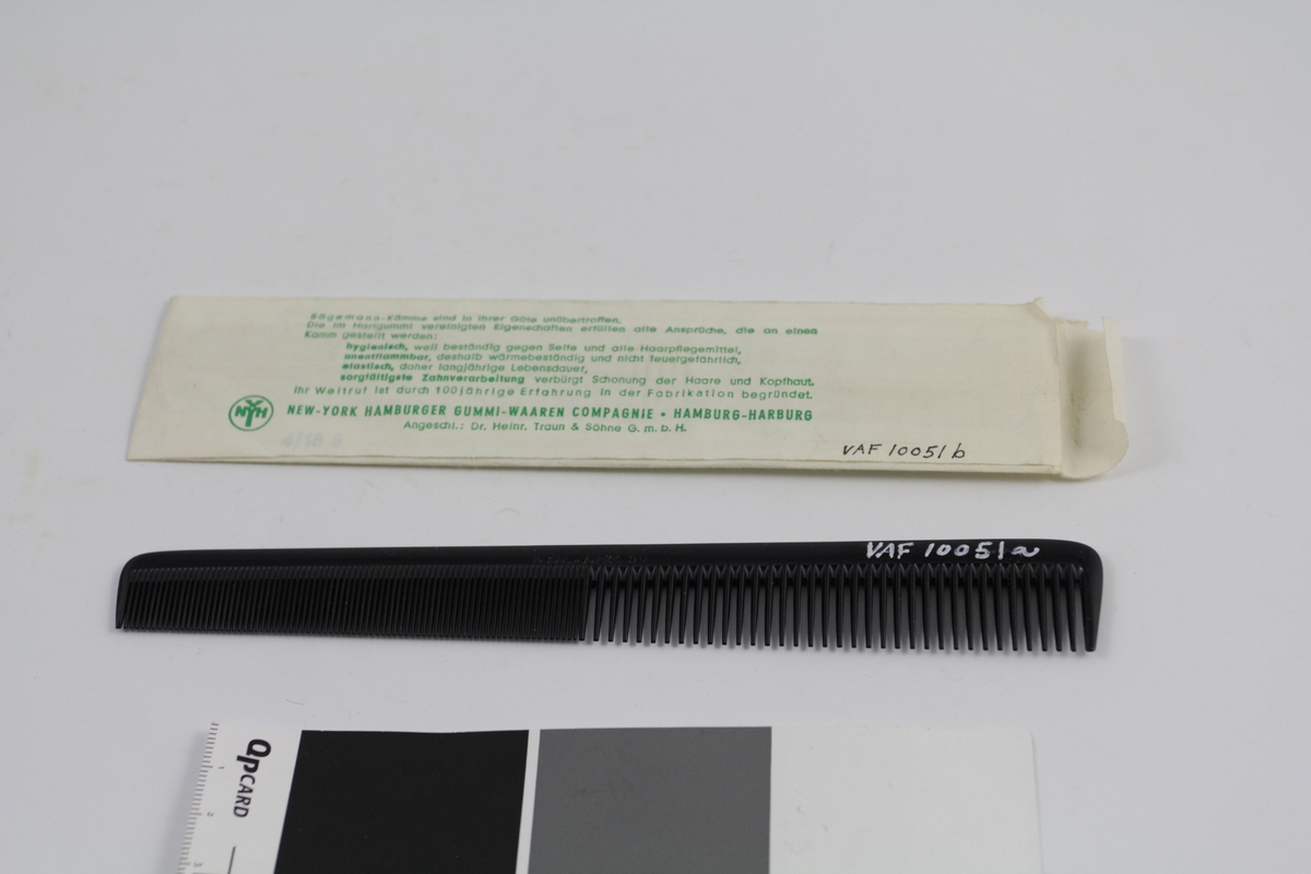 1 stk. kam (a) i original papirpose (b). Den ene halvdelen av kammen grovtannet, den andre fintannet - smalner litt mot den fintannede siden. Papirpose med åpning i den ene kortsiden, laget av ett stykke papir, påtrykket tekst.
