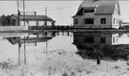 Parti av Rödesund, i huset till vänster som byggdes 1904 hade Ester Byqvist sin fotoateljé. Utrymmet framför husen arrenderades av Ester Byqvist. Denna öppna del innesluter numera en bilparkering och torghandel. Fotot är taget år 1921. Kortet är från K-A Hanssons album.