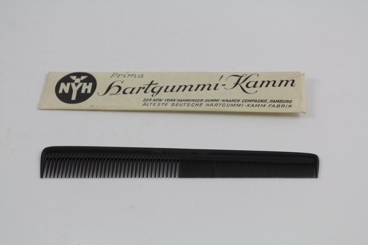 Kam (a) i original papirpose (b). Den ene halvparten fintannet, den andre grovere. Kammen smalner litt mot den fintannede delen. Papirpose av ett stykke papir med trykket tekst (se foto).