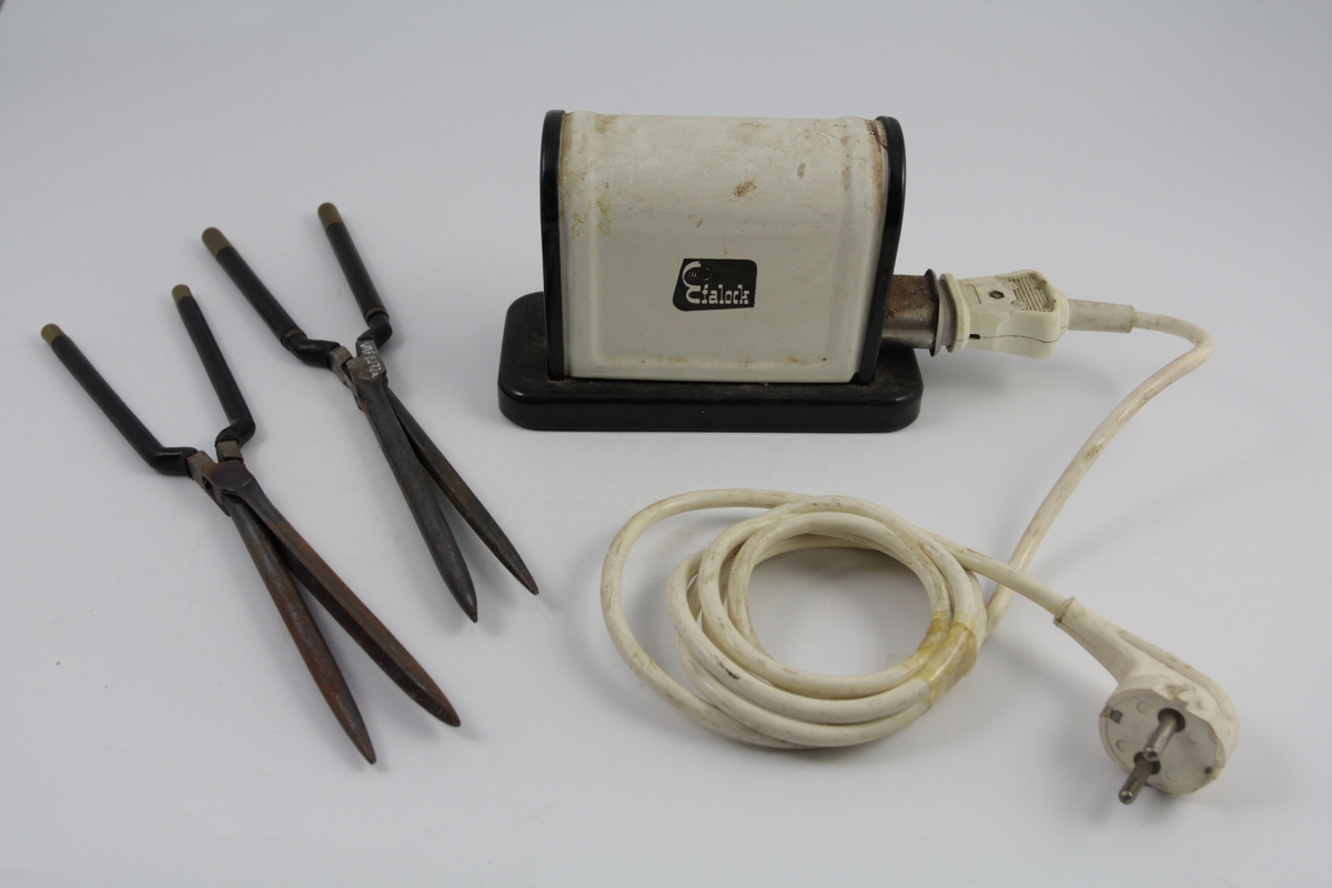 Eletrisk krølltang bestående av fire deler:
a-b) krølltenger: 2 stk. sylindriske håndtak (a kan beveges).  Når håndtakene føres sammen, presses sylinder i andre enden ned i hul del. 
c) elektrisk varmeapparat, uttak støpsel og ledning på den ene siden. Rektangulær sokkel. Påsatt rektangulær del med avrundet overside. Kortside: inntak for to krølltenger. Oval åpning. 
d) Ledning med kontakter.