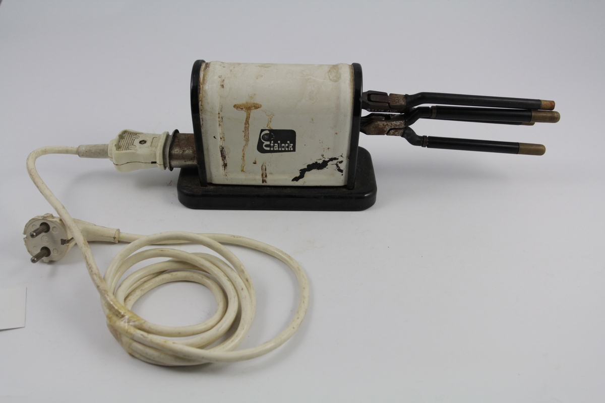 Eletrisk krølltang bestående av fire deler:
a-b) krølltenger: 2 stk. sylindriske håndtak (a kan beveges).  Når håndtakene føres sammen, presses sylinder i andre enden ned i hul del. 
c) elektrisk varmeapparat, uttak støpsel og ledning på den ene siden. Rektangulær sokkel. Påsatt rektangulær del med avrundet overside. Kortside: inntak for to krølltenger. Oval åpning. 
d) Ledning med kontakter.