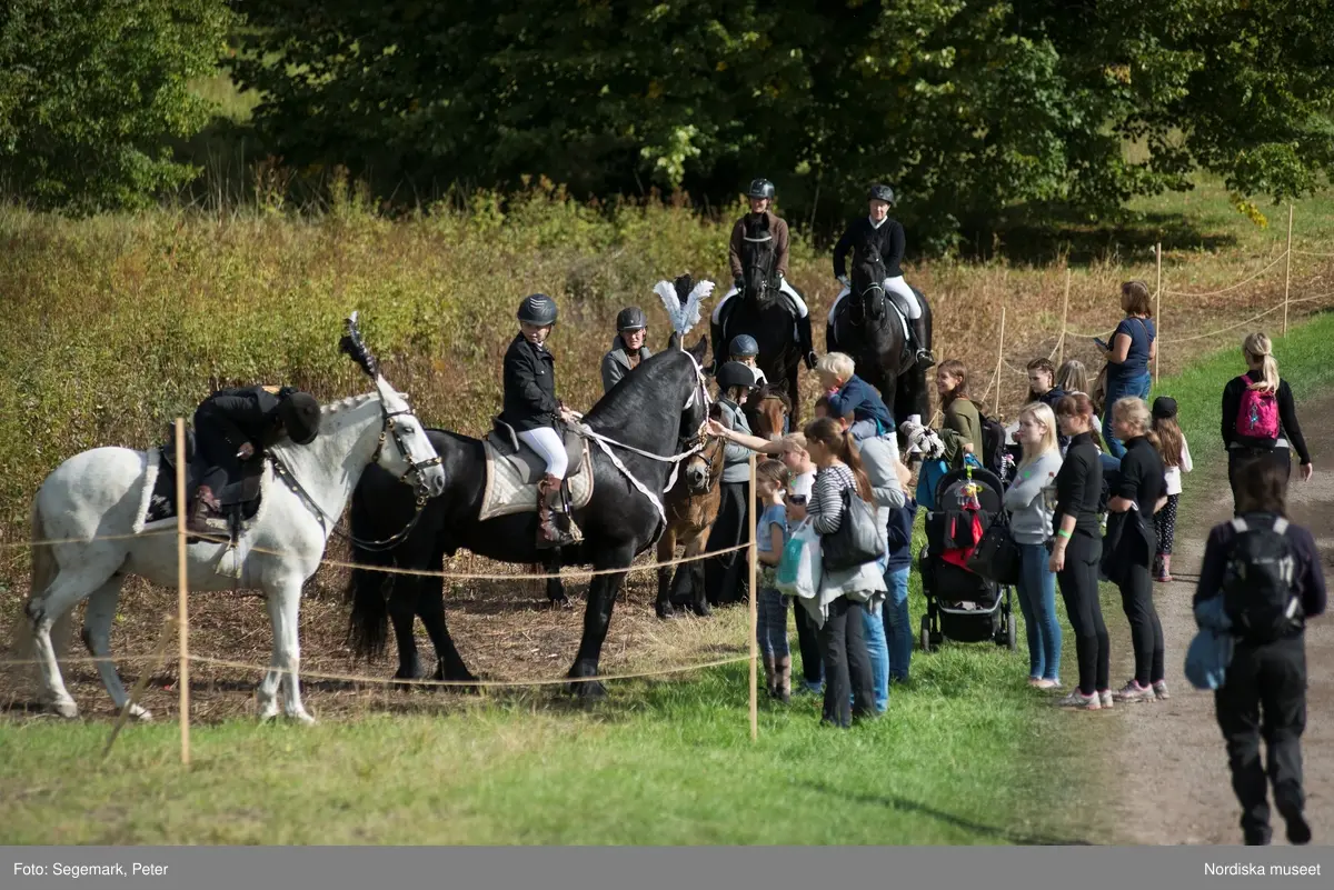 Hästfesten på Tyresö slott med konferencier Owe Sandström, Slottshästen. Hästar, ryttare och ekipage med vagn eller käpphäst tävlar och visar upp sig i parken bland åskådare som besöker evenemanget.