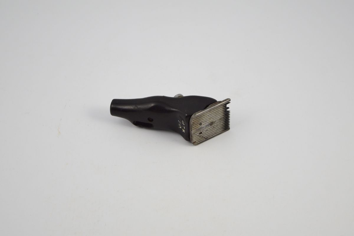 Form: Rektangulært metallbrett ("kniv") med pigger i den ene enden, spor langs undersiden. Mellom denne og maskindel et annet brett ("kniv") med pigger. Når apparatet slås på, beveger denne seg. Apparatet står skrått på kniven. Avrundede, ujevne former. Sirkulær skrue overside. Uttak (ledning) i ender.