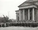 Matroser uppställda framför Tyska kyrkan i militär march. I samlingen syns också civila åskådare.