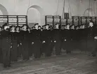 Unga matroser uppställda på rad under inspektion. På höger och vänster sida syns två sjöbefäl varav en gör honör.
