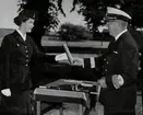 En kvinna ur Lottakåren mottager en pokal av konteramiral Samuelson, båda iförda i uniformer.