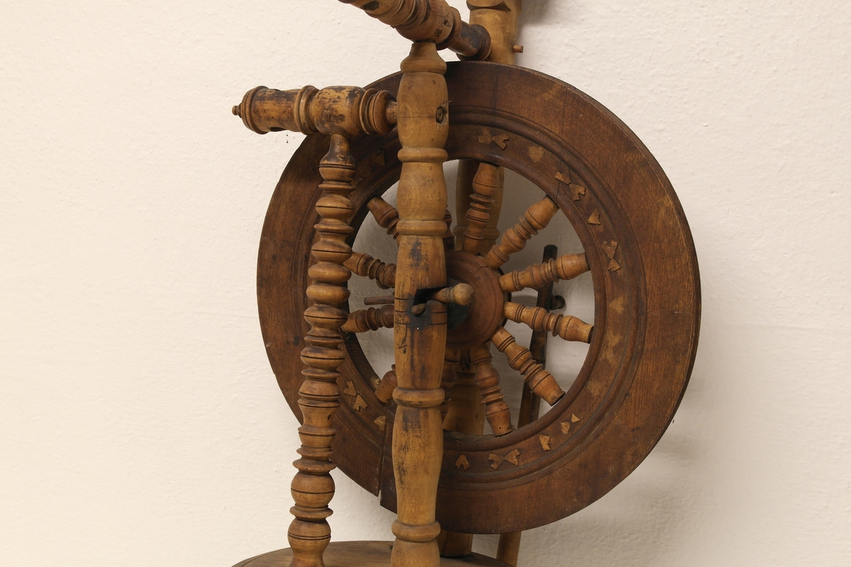 Stående hjulrokk i tre med spinneapparatet plassert over hjulet. Rokken har opprinnelig hatt tre bein.