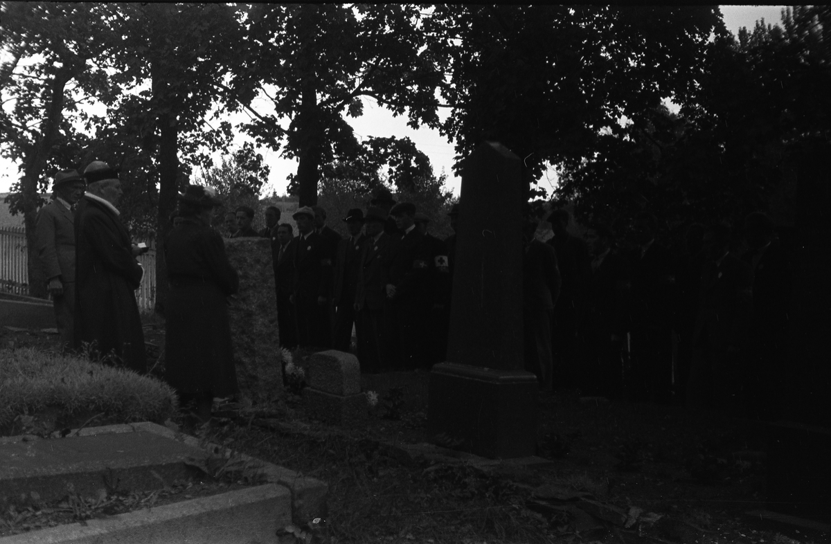 Fem bilder fra en høytidelighet på Hoff kirkegård, sannsynligvis 16. september 1945 som var en minnedag for de som falt under 2.verdenskrig.. Markering foregår sannsynligvis ved graven til Bjarne Fodstad som falt ved Haug kirke i Vardal 21.april 1940. Prosesjonen utgjøres av, foruten sogneprest Ingebrigt Hole, medlemmer av Milorg-gruppa Kapp/Lena. På bilde nr. 1 er også følgende personer identifisert: Johan Nygaard i venstre bildekant, Carsten Aschim bakerst i rekka nærmest Nygaard, og trolig Harald Tørnby som nr. 2 i rekke nr. 2.