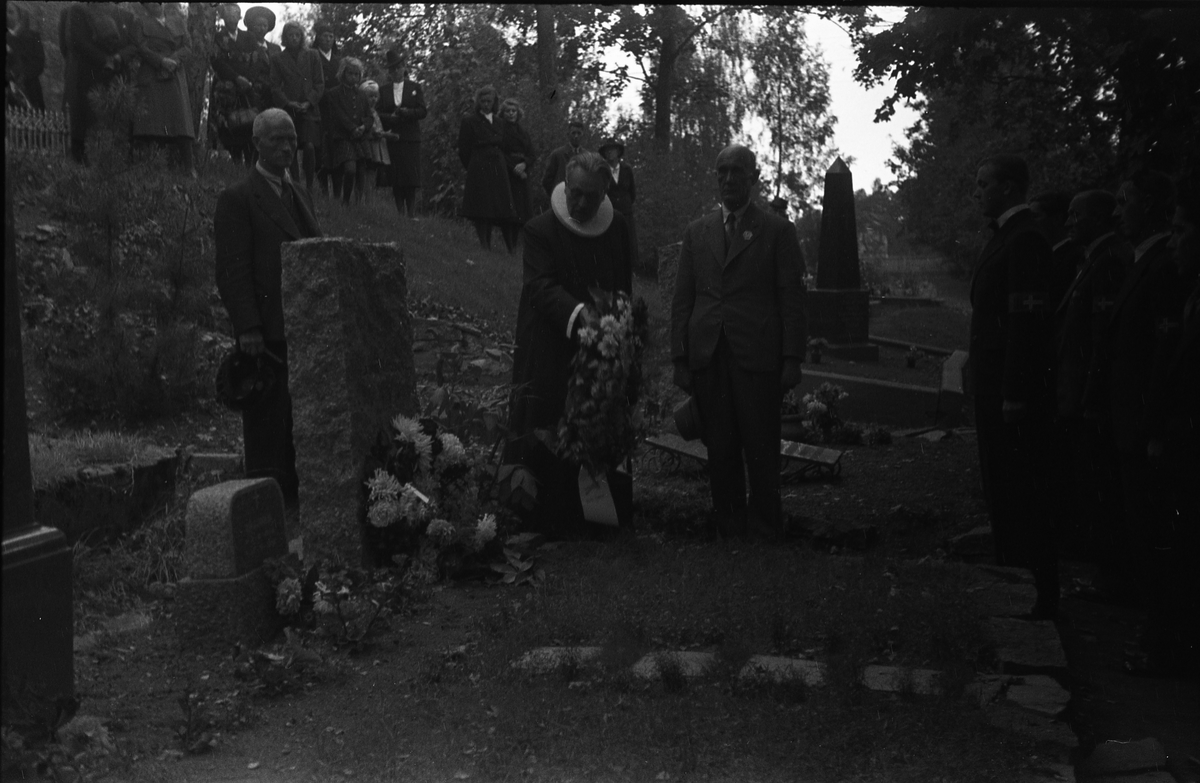 Fem bilder fra en høytidelighet på Hoff kirkegård, sannsynligvis 16. september 1945 som var en minnedag for de som falt under 2.verdenskrig.. Markering foregår sannsynligvis ved graven til Bjarne Fodstad som falt ved Haug kirke i Vardal 21.april 1940. Prosesjonen utgjøres av, foruten sogneprest Ingebrigt Hole, medlemmer av Milorg-gruppa Kapp/Lena. På bilde nr. 1 er også følgende personer identifisert: Johan Nygaard i venstre bildekant, Carsten Aschim bakerst i rekka nærmest Nygaard, og trolig Harald Tørnby som nr. 2 i rekke nr. 2.