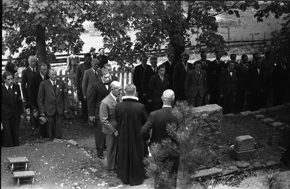Fem bilder fra en høytidelighet på Hoff kirkegård, sannsynligvis 16. september 1945 som var en minnedag for de som falt under 2.verdenskrig.. Markering foregår sannsynligvis ved graven til Bjarne Fodstad som falt ved Haug kirke i Vardal 21.april 1940. Prosesjonen utgjøres av, foruten sogneprest Ingebrigt Hole, medlemmer av Milorg-gruppa Kapp/Lena. På bilde nr. 1 er også følgende personer identifisert: Johan Nygaard i venstre bildekant, Carsten Aschim bakerst i rekka nærmest Nygaard, og trolig Harald Tørnby som nr. 2 i rekke nr. 2.