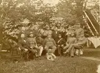 Officerare, soldater och civilklädda personer i trädgård utanför officersmässen, Karlsborgs garnison, augusti 1882.