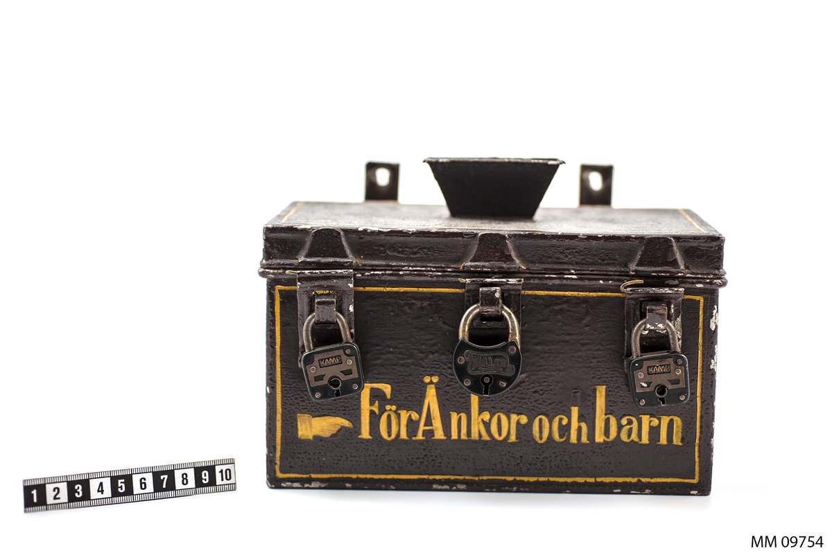 Sparbössa rektangulär, på översidan försedd med lock och öppning för pengarna, tre rörliga överfall för låsning med tre stycken hänglås.