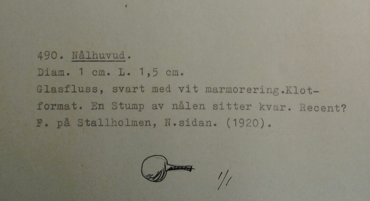 Klotformad knapp av svart, opak glasfluss med vit marmorering. Matt glasyta. En stump av järnöglan sitter kvar. Tidigare tolkad som en recent nål. Se Referenser/Digitala objekt för liknande knapp i 1500-1600-talskontext.