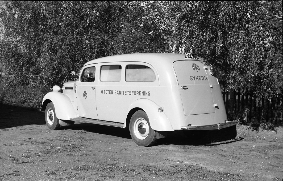 Ambulanse, muligens den første anskaffet av Østre Toten Sanitetsforening. Serie på 12 bilder fra september 1948. Kvinnen på bilde nr. åtte er Gjertrud Solem som trolig er sanitetsforeningens representant, mens mannen på bilde nr. sju, og som nok er sjåføren, er Anders Skolby fra Kapp. Han ble senere sjåfør for kronsprins Olav på Skaugum, og etter det privatsjåfør for Anders Jahre .