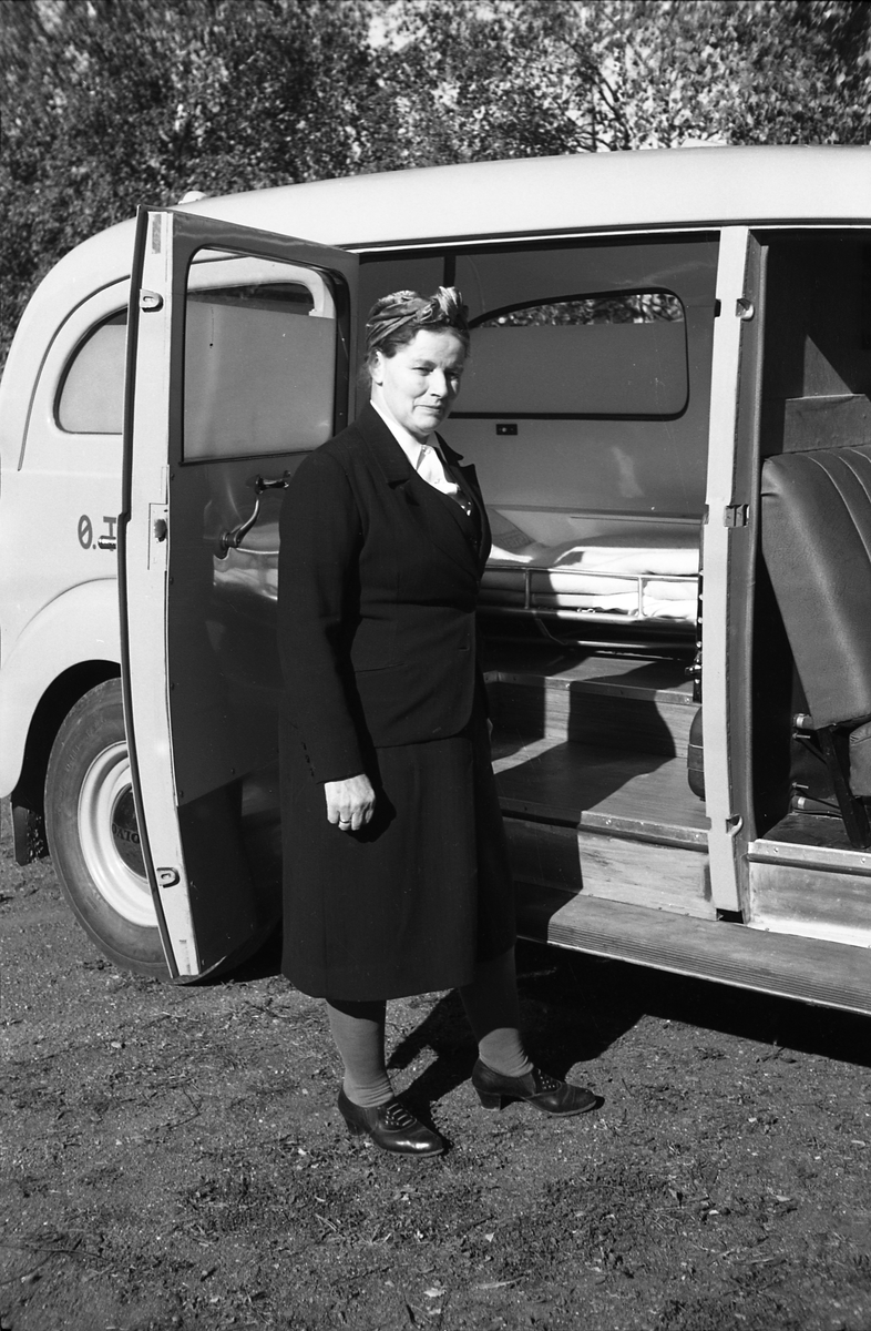 Ambulanse, muligens den første anskaffet av Østre Toten Sanitetsforening. Serie på 12 bilder fra september 1948. Kvinnen på bilde nr. åtte er Gjertrud Solem som trolig er sanitetsforeningens representant, mens mannen på bilde nr. sju, og som nok er sjåføren, er Anders Skolby fra Kapp. Han ble senere sjåfør for kronsprins Olav på Skaugum, og etter det privatsjåfør for Anders Jahre .