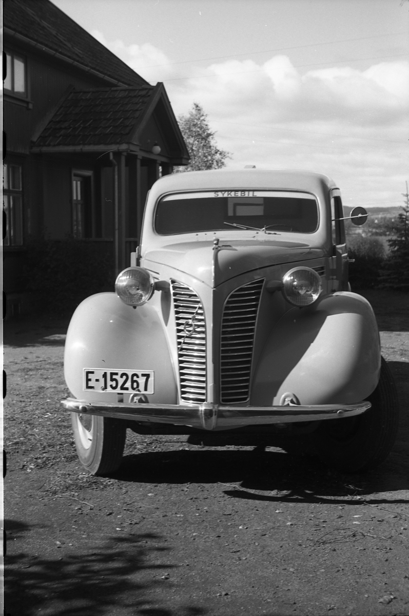 Ambulanse, muligens den første anskaffet av Østre Toten Sanitetsforening. Serie på 12 bilder fra september 1948. Kvinnen på bilde nr. åtte er Gjertrud Solem som trolig er sanitetsforeningens representant, mens mannen på bilde nr. sju, og som nok er sjåføren, er Anders Skolby fra Kapp. Han ble senere sjåfør for kronsprins Olav på Skaugum, og etter det privatsjåfør for Anders Jahre .