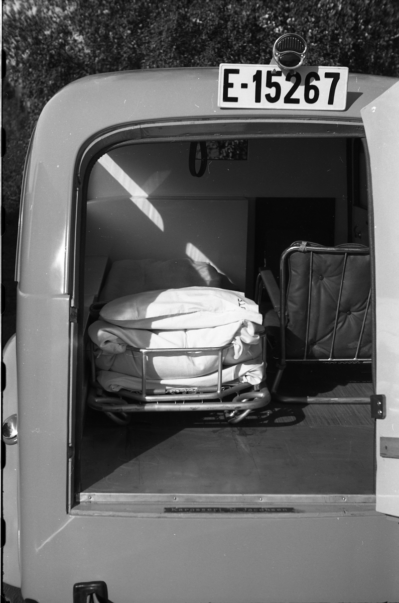 Ambulanse, muligens den første anskaffet av Østre Toten Sanitetsforening. Serie på 12 bilder fra september 1948. Kvinnen på bilde nr. åtte er Gjertrud Solem som trolig er sanitetsforeningens representant, mens mannen på bilde nr. sju, og som nok er sjåføren, er Anders Skolby fra Kapp. Han ble senere sjåfør for kronsprins Olav på Skaugum, og etter det privatsjåfør for Anders Jahre .