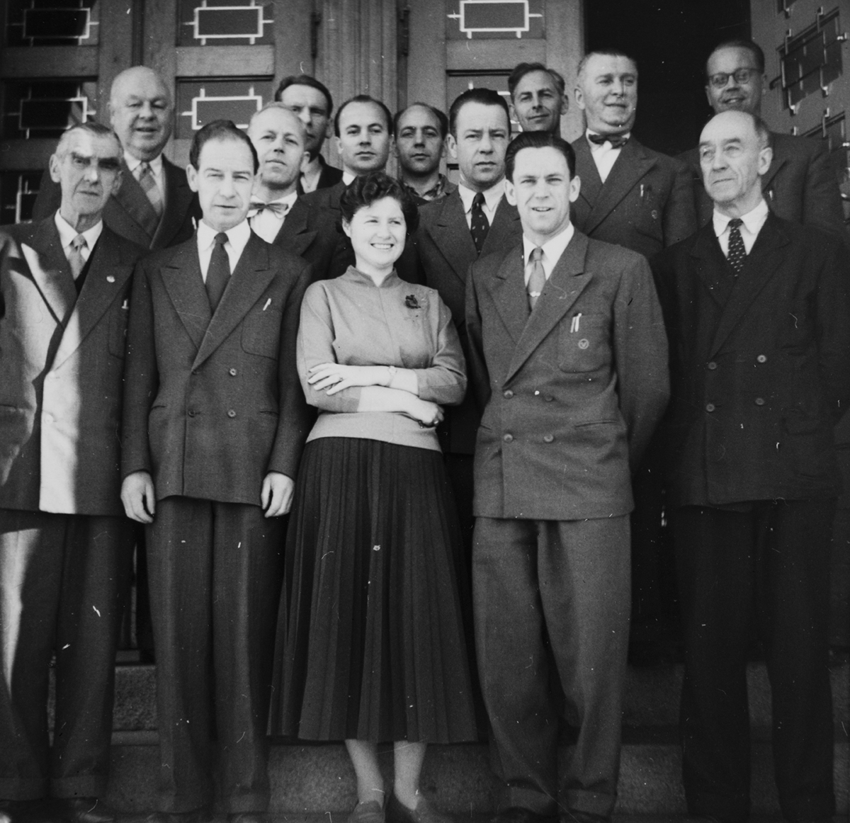 Vinmonopolet,  Strandgata, Hamar. Gruppe 14 ansatte. Foran f.v. Sigurd Olsen, Torvald Bakken, Berit Rustad, Magne Hval, Jørgen Svendsen. Bak f.v. Christian Platou, Sigurd Hove, Arne Hoel, Bjørn Bøhn, Willy Olsen, Reidar Amundsen, Per Mølstad, Sigurd Larsen, Arne Larsen. Ca. 1950.