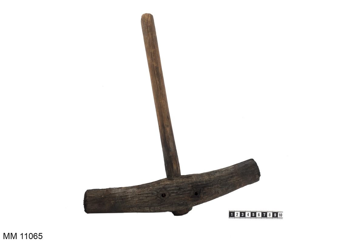 Drevhammare av trä. Hammaren tillverkad under år 1708. Bågformad, på mitten försedd med genomgående runt träskaft. Nitar vid skaft och ringar kring slagen saknas (är sönderrostade).