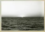 Bilden föreställer en solnedgång i horisonten, där en klar himmel möter hav. Bilden är tagen under minfartyget Älvsnabbens långresa 1966-1967.