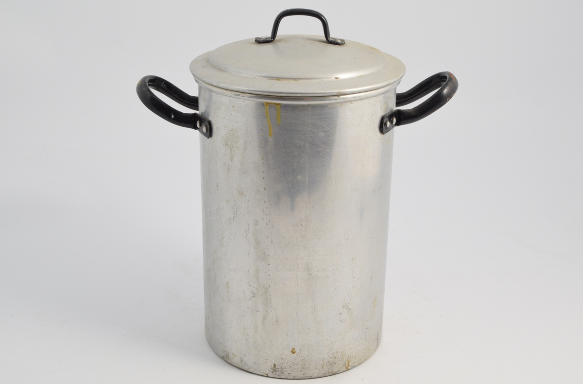 Aluminiumskjele med lokk og ot haker. To aluminiums innsatser; en med små hull og en med store hull - begge på ben. Brukt til varmebehandling (desinfisering) av kolber og utstyr og enkelte legemidler. Vann ble fylt opp til bunnen av risten og varmet opp.